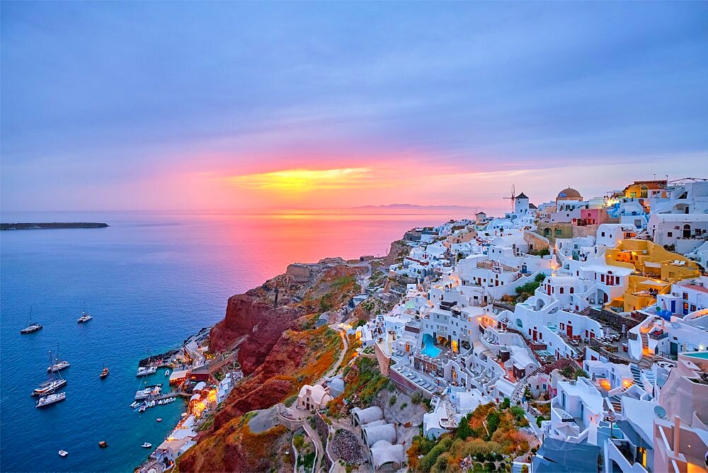 Famous greek iconic selfie spot tourist destination Oia village with traditional white houses and windmills in Santorini island on sunset in twilight, Greece, Europe