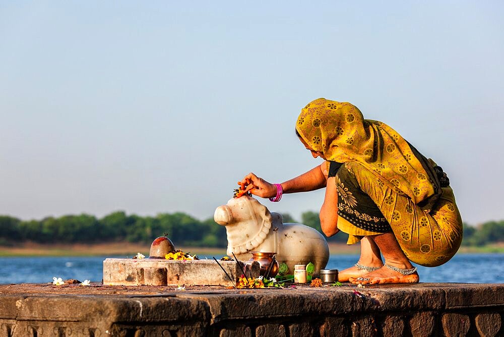 MAHESHWAR, INDIA, APRIL 26: Indian woman performs morning pooja on sacred river Narmada ghats on April 26, 2011 in Maheshwar, Madhya Pradesh, India. To Hindus Narmada is one of 5 holy rivers of India