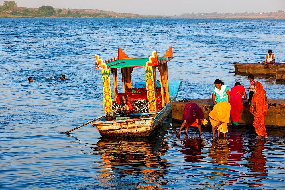 MAHESHWAR, INDIA, APRIL 26, 2011: Indian women doing morning pooja on ghats of sacred Narmada river. Maheshwar, Madhya Pradesh, India, Asia