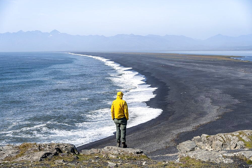 Tourist looking over long black sand beach, Reynisfjara Beach, South Iceland, Iceland, Europe