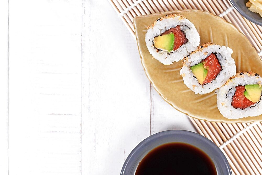 Sushi inside out rolls with salmon, avocado and sesame on small leaf shaped plateSushi inside out rolls with salmon, avocado and sesame on small leaf shaped plate