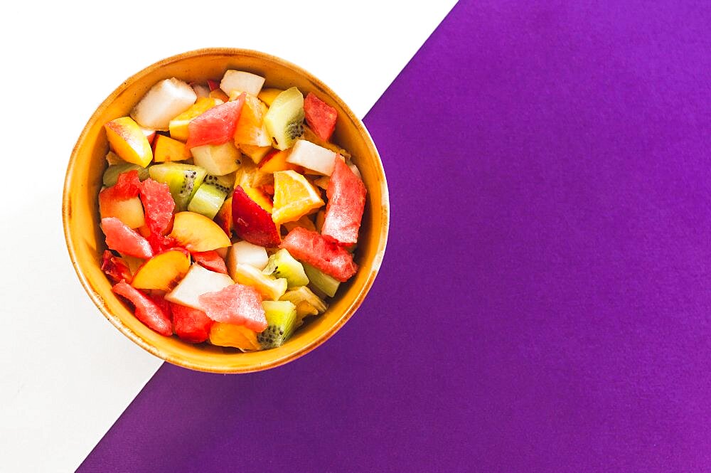 Bowl fruit salad white purple background