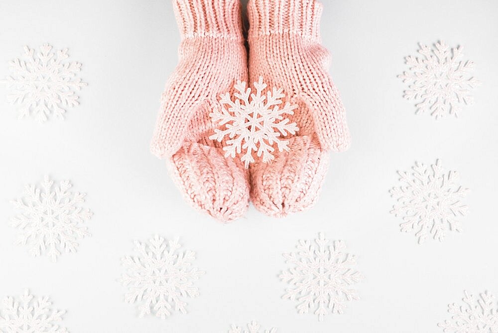 Human hands mittens with paper snowflake