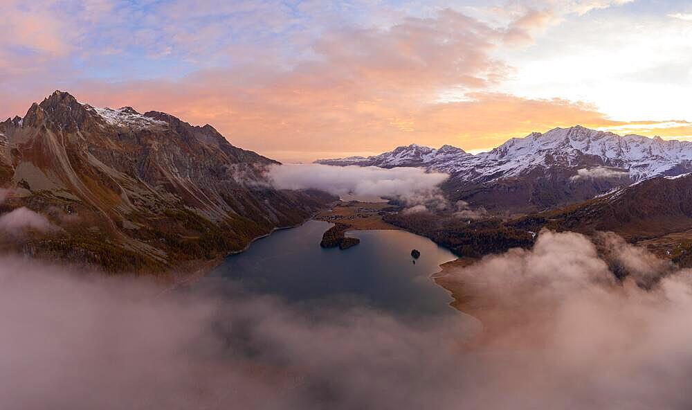 Aerial view over the fog and Lake Sils in front of sunrise in autumn, Canton Graubuenden, Switzerland, Europe