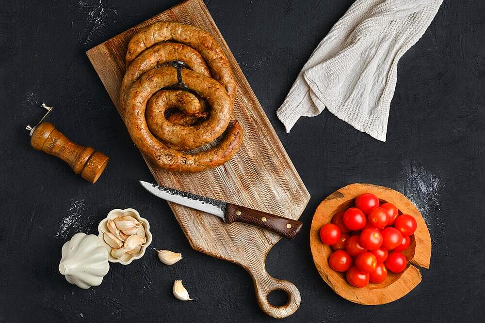 Horse meat sausage with garlic rolled on wooden cutting board