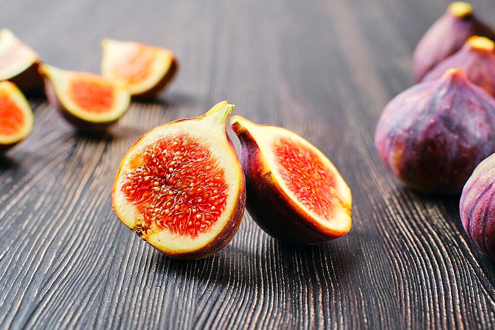 Fresh figs, whole and cut on slices on wooden table