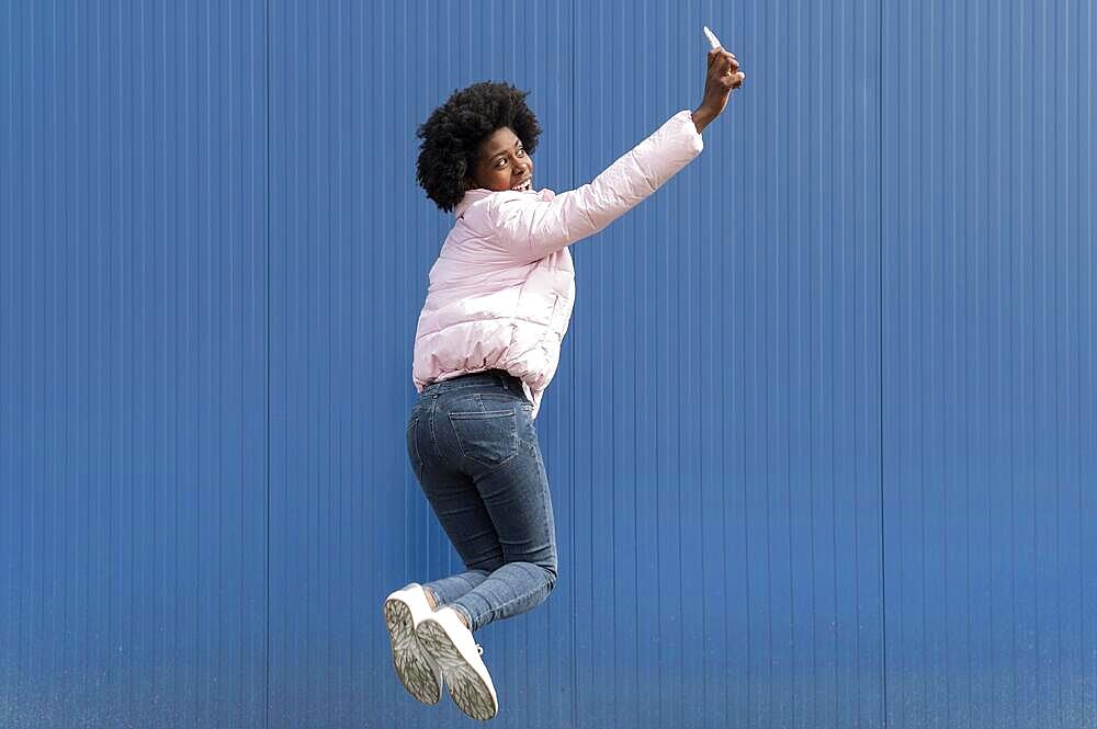 portrait young woman with mobile jumping