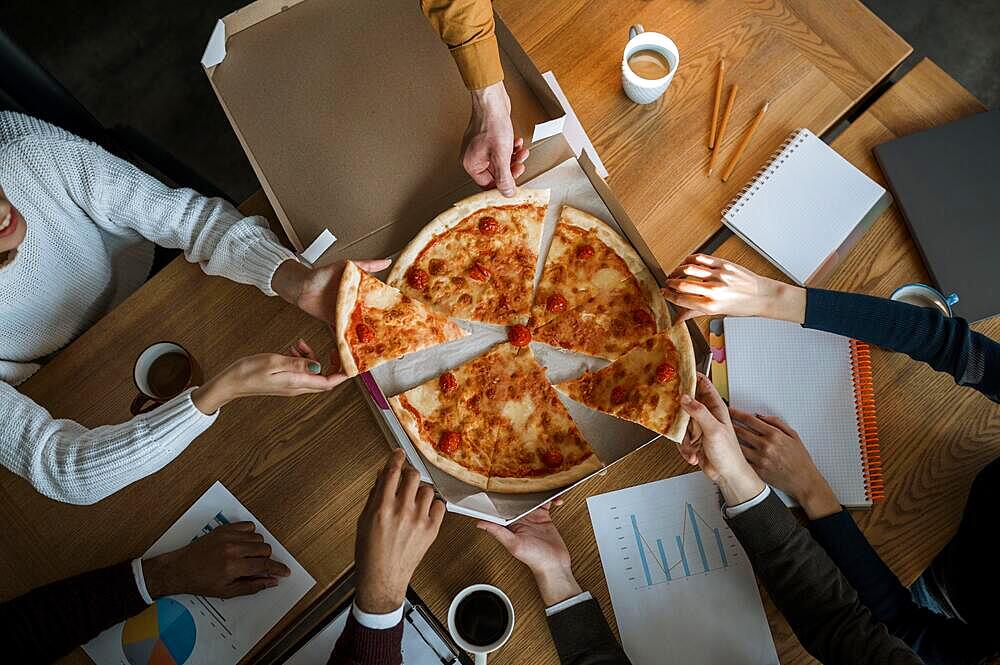 Top view colleagues having pizza during office meeting break