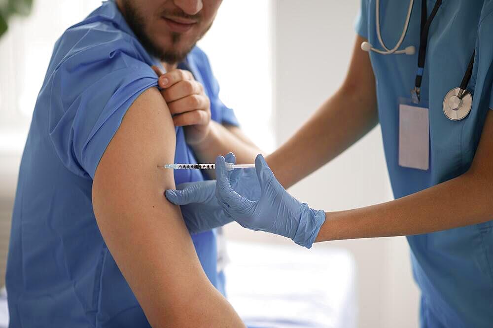 Female doctor vaccinating her colleague