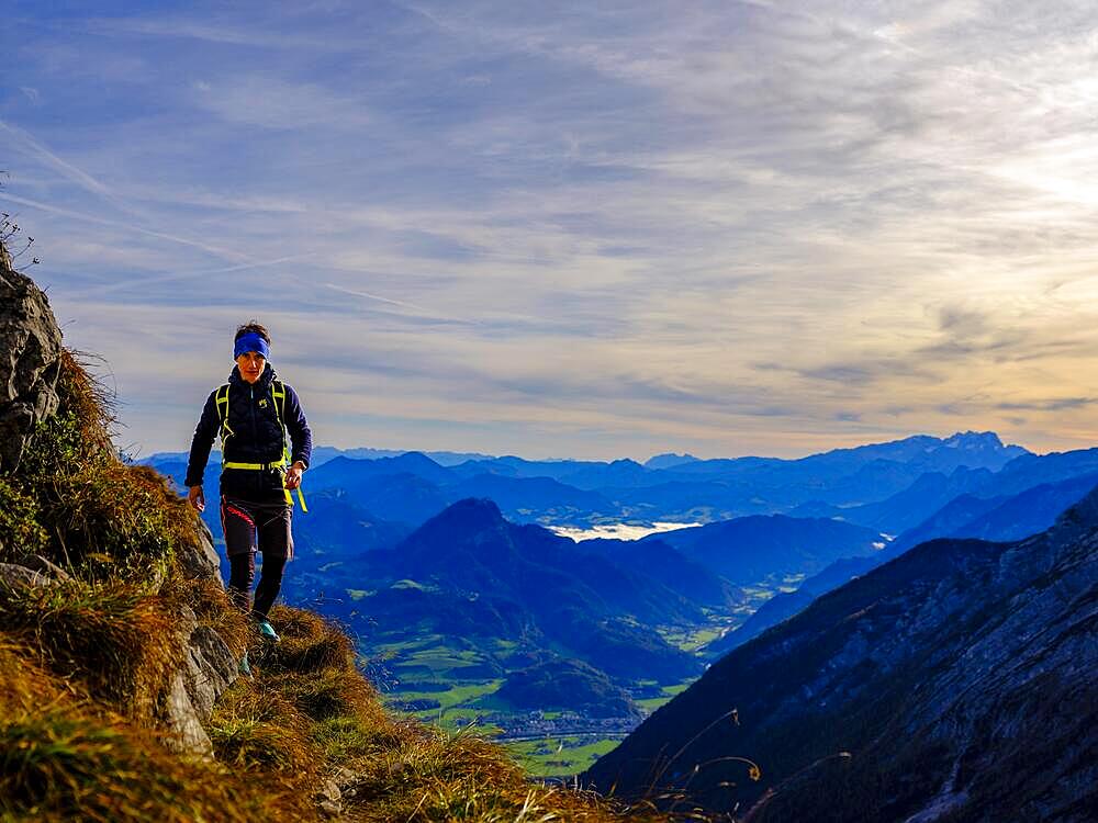 Mountaineer walking on a narrow path above the Salzach valley, in the background Osterhorn group and Hoher Dachstein, Golling, Salzburger Land, Austria, Europe