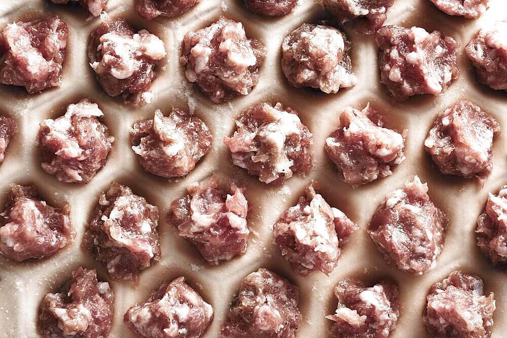 Handmade homemade dumplings on a metal tray on a wooden background with flour. Diy meat dumplings