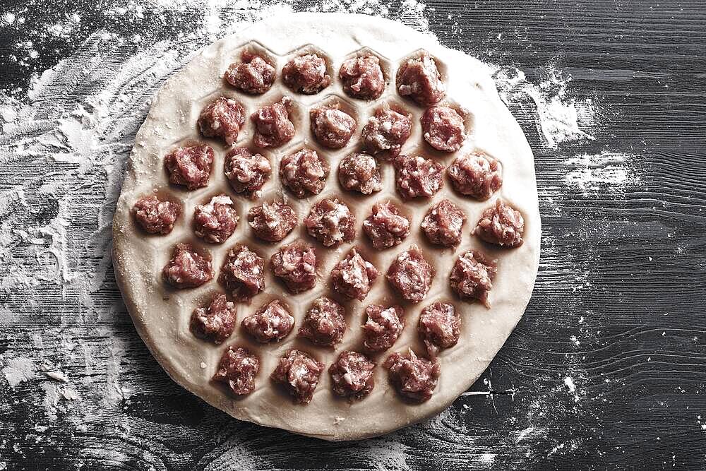 Handmade homemade dumplings on a metal tray on a wooden background with flour. Diy meat dumplings