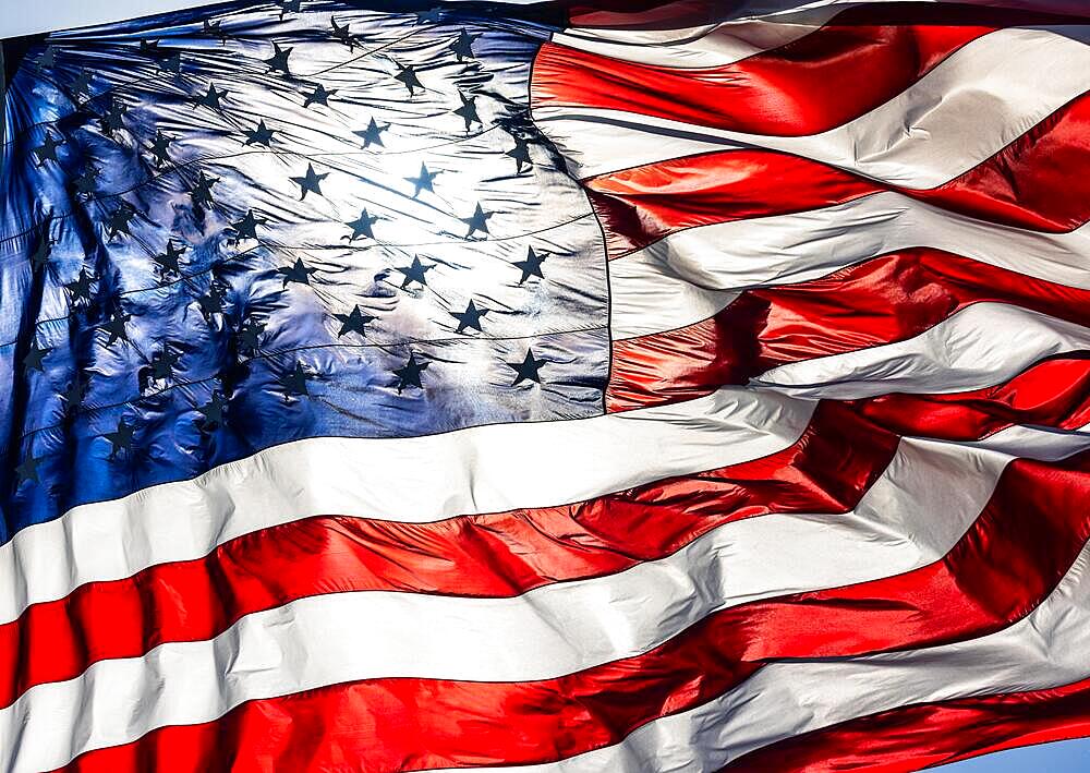 Backlit american flag waving in wind against a deep blue sky