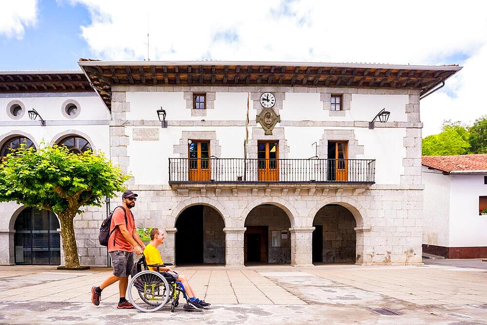 A disabled person in a wheelchair walking through the town square having fun with a friend