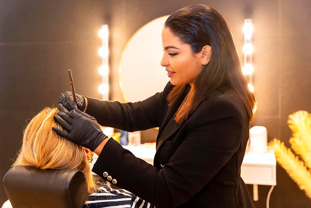 Latin woman in a cosmetic shop fixing eyebrows to the client