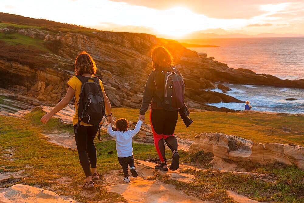 Lgbt couple of women with a child walking in the sunset on the coast by the sea, family lifestyle