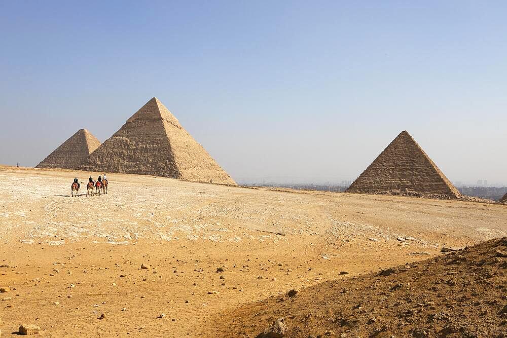 Camel riding on the west side of the pyramids, in the background in the haze the Nile Valley, Giza, Cairo, Egypt, Africa