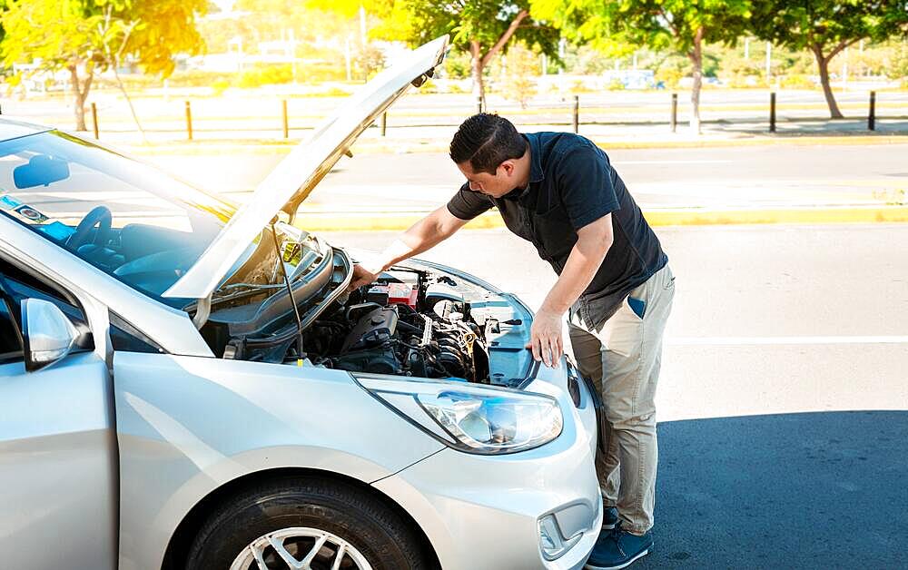 Driver checking the oil in his vehicle. Person checking the oil level of his car in the street. Driver inspecting car oil level