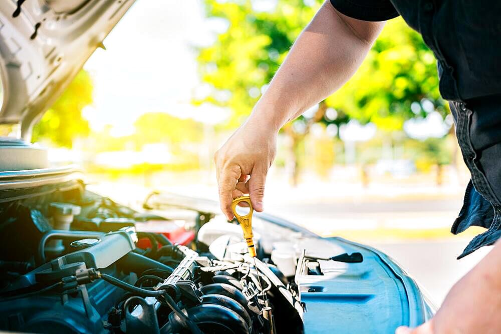 Man hand checking oil to car with copy space. People hand inspecting car oil level. Driver hand inspecting car oil level