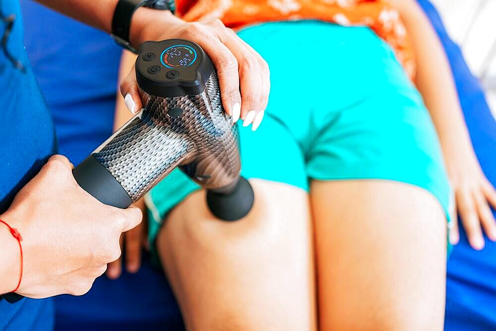 Chiropractor using massage gun on patient leg, Physiotherapist using massage gun to relieve muscle pain, Percussion or vibration therapy. Physiotherapist using massage gun on patient