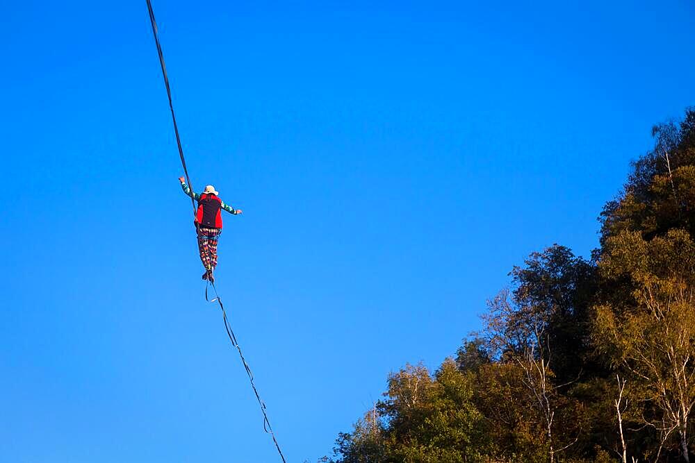 LANZO, ITALY - CIRCA OCTOBER 2020: Slackline athlete during his performance. Concentration, balance and adventure in this dynamic sport