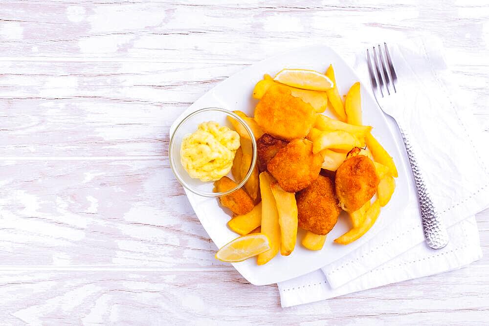 Fish and chips with dip and lemon on white plate