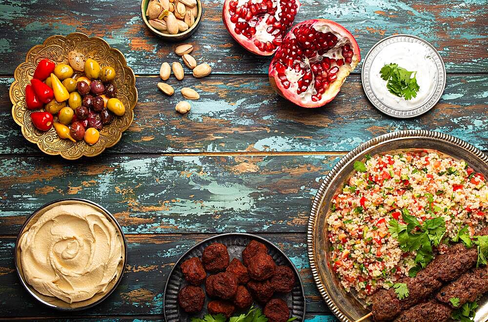 Various Turkish dishes: meat kebab with tabbouleh salad, falafel, hummus, olives, pistachios and Middle Eastern meze on wooden table top view with copy space. Ethnic arab food, cuisine of Turkey