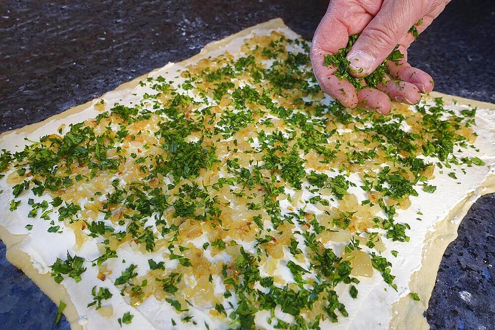 Swabian cuisine, preparing hearty snail pasta, topping raw yeast dough, herbs, onions, sour cream, small hearty snail pasta, salty yeast pastry, yeast dough, bake, out of the oven, typical Swabian reinterpreted, party pastry, finger food, appetisers for on the go, traditional cuisine, food photography, studio, mans hand, Germany, Europe