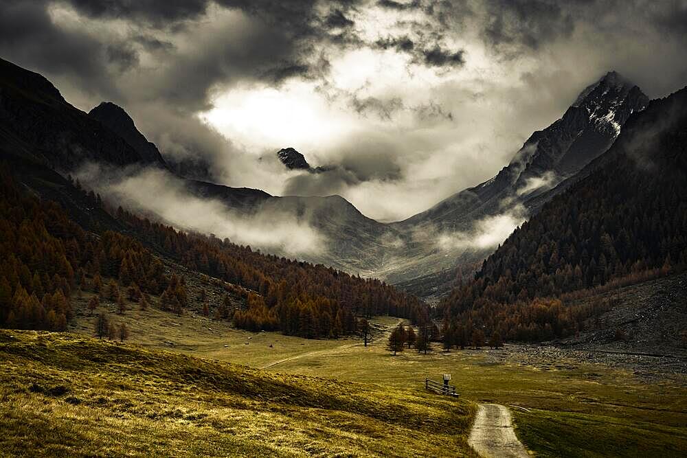 Way cross with path in autumnal mountain landscape with threatening cloudy sky, Pfossental, Merano, Vinschgau, South Tyrol, Italy, Europe