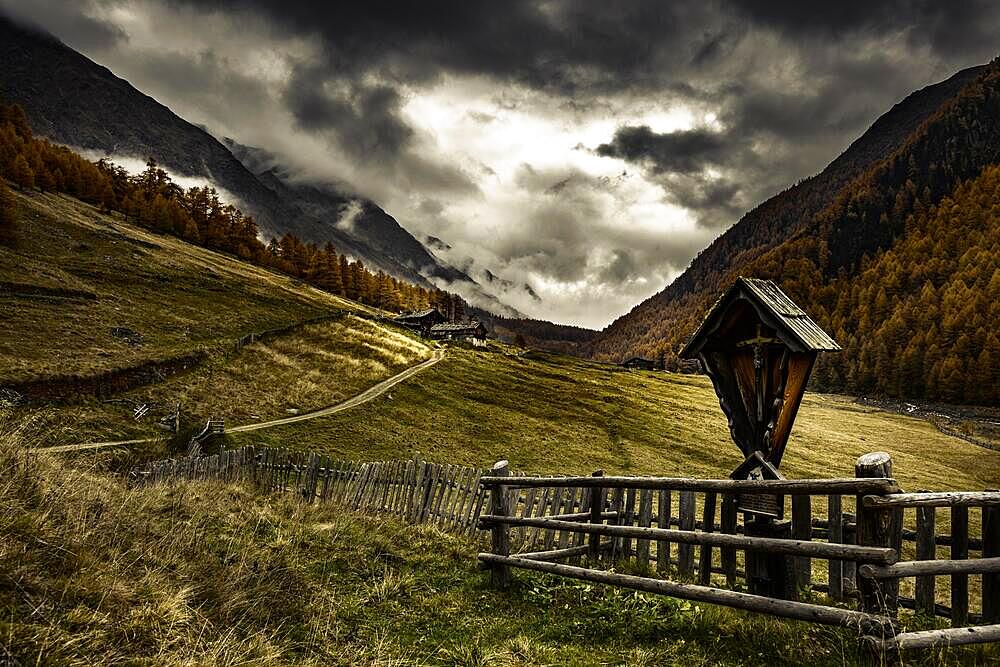 Way cross with alpine hut in autumnal mountain landscape with threatening cloudy sky, Pfossental, Merano, Vinschgau, South Tyrol, Italy, Europe