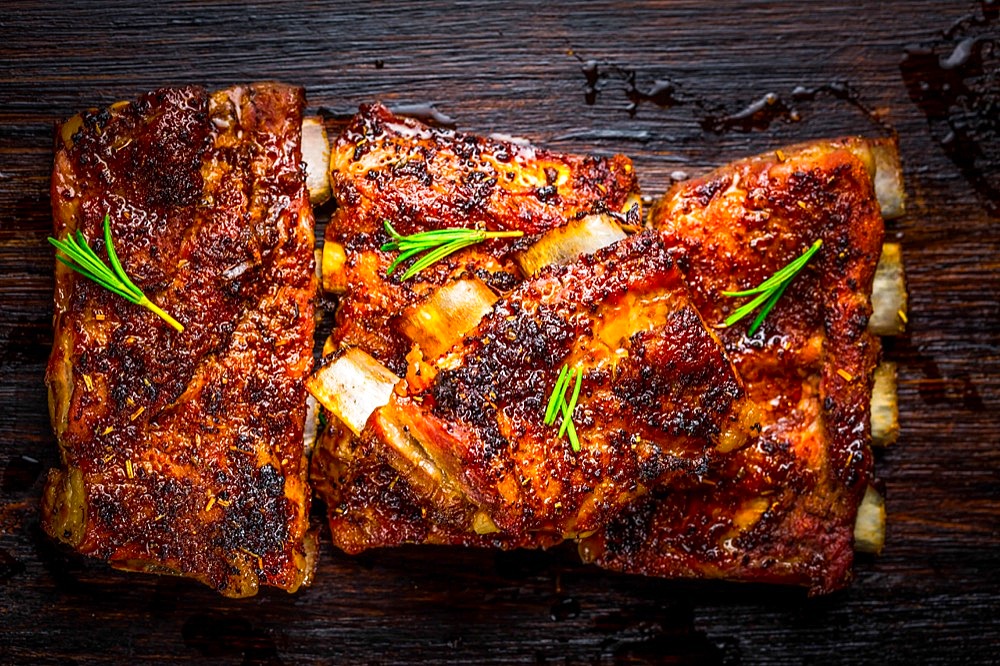 Hot spare ribs with herbs and spicies on black wooden background