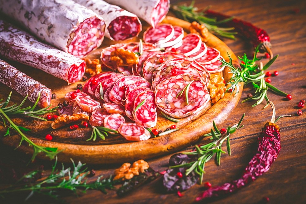 Charcuterie - Assortment of air-dried salami and sausage on wooden cutting board with spices