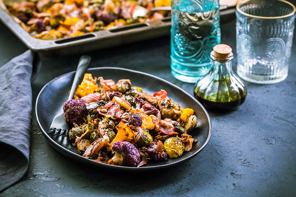 Healthy food - Baked vegetables with Purple Brussels sprouts, broccoli, cauliflower and onions on baking sheet