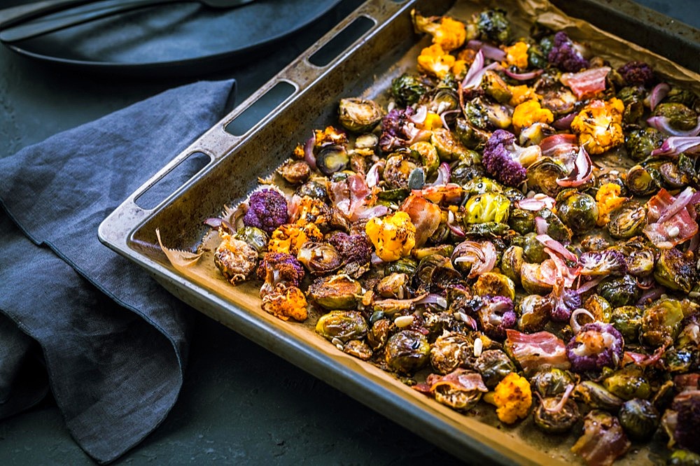 Healthy food - Baked vegetables with Purple Brussels sprouts, broccoli, cauliflower and onions on baking sheet