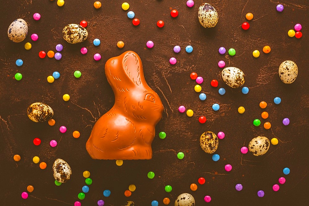 Delicious chocolate easter eggs, bunny and sweets on dark brown background