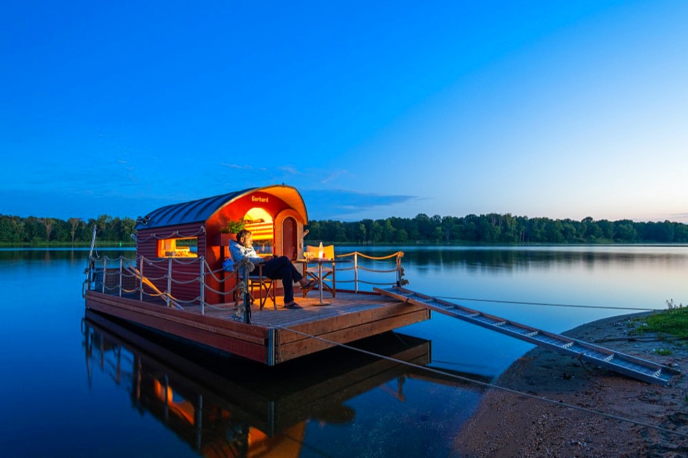 Man sitting in the blue hour on a houseboat, house raft, in front of the island Kiehnwerder, Breitlingsee, Brandenburg an der Havel, Havelland, Brandenburg, Germany, Europe