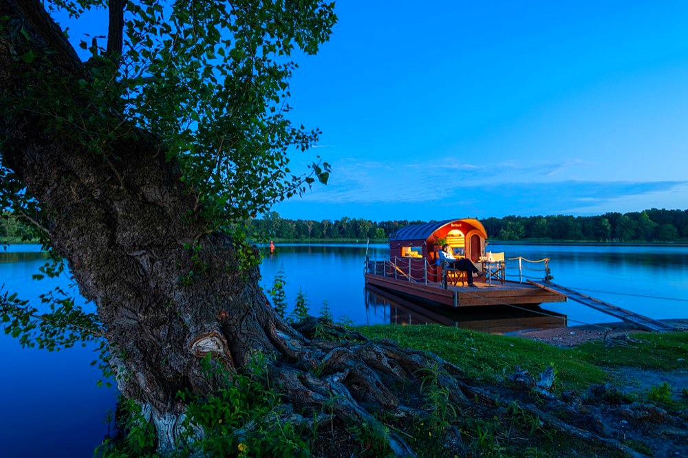Man sitting in the blue hour on a houseboat, house raft, in front of the island Kiehnwerder, Breitlingsee, Brandenburg an der Havel, Havelland, Brandenburg, Germany, Europe