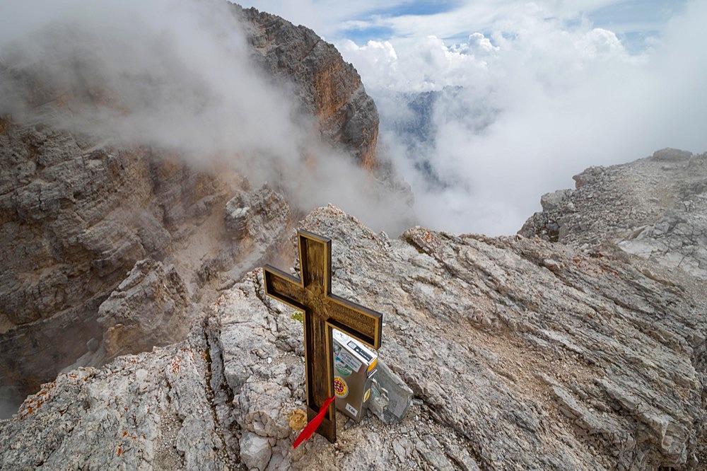 View obscured by clouds from the top of the Cima di Mezzo mountain (3154 m) with a beautiful cross on the top., Dolomites, Italy, Europe