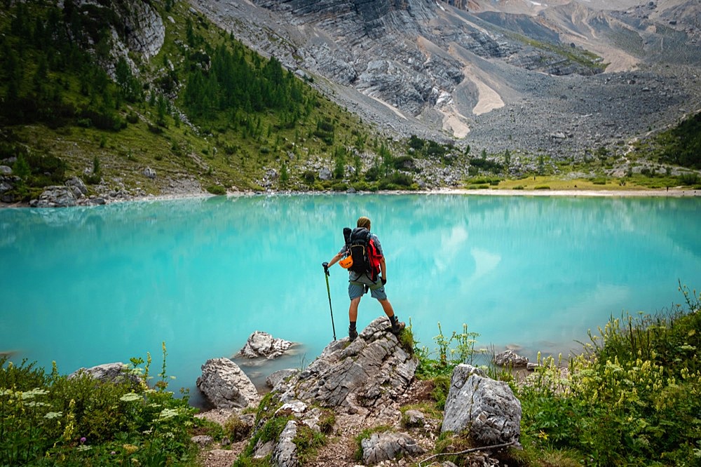 Tourist posing for a photo against the background of the beautiful Lago di Sorapis lake in the Italian Dolomites, Dolomites, Italy, Europe