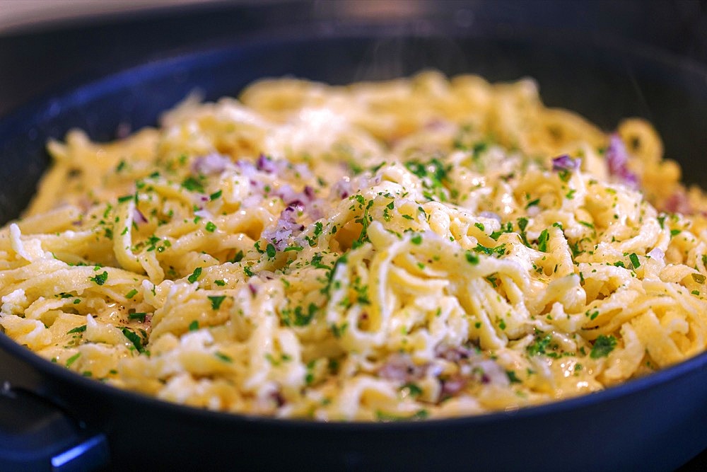 Swabian Kaesspaetzle with onions and herbs stew in a pan