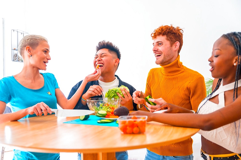 Group of friends preparing vegetarian food. Preparing the salad and having fun in the kitchen