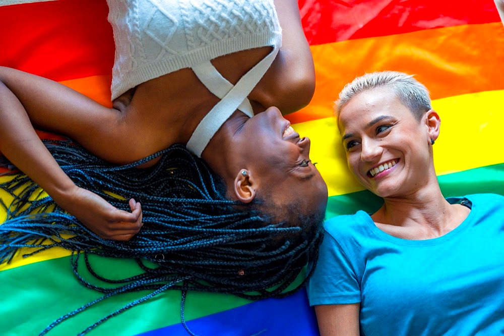 Beautiful lesbian couple over rainbow flag, lgbt concept, romantic pose