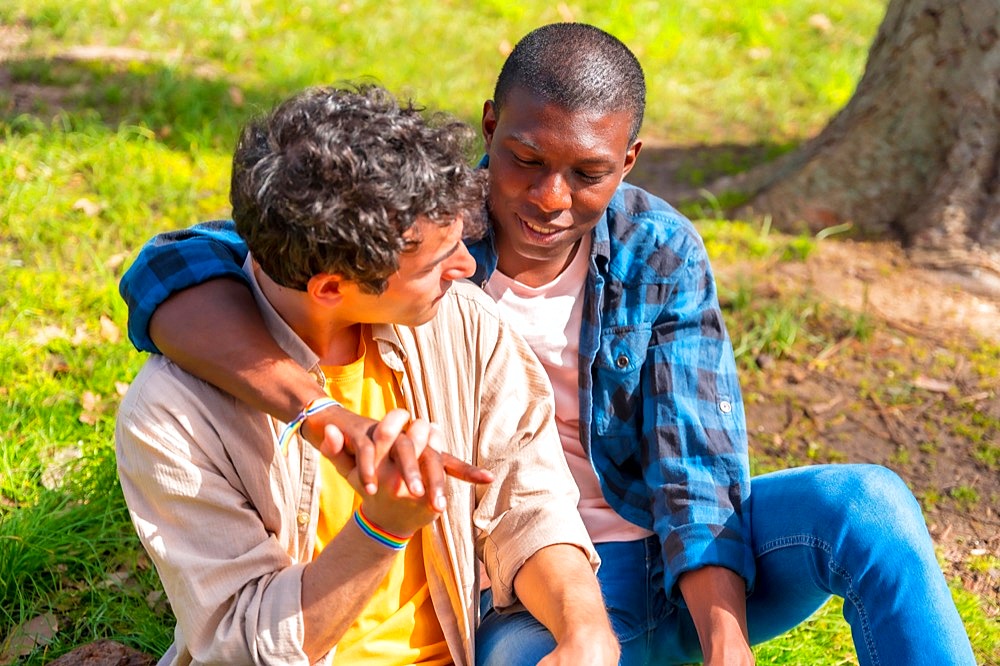 Couple of multiethnic gay men talking quietly in the park, lgbt concept