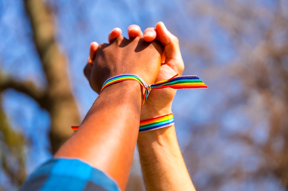 Hands of a multiethnic gay male couple holding hands, lgbt concept, homosexual guys