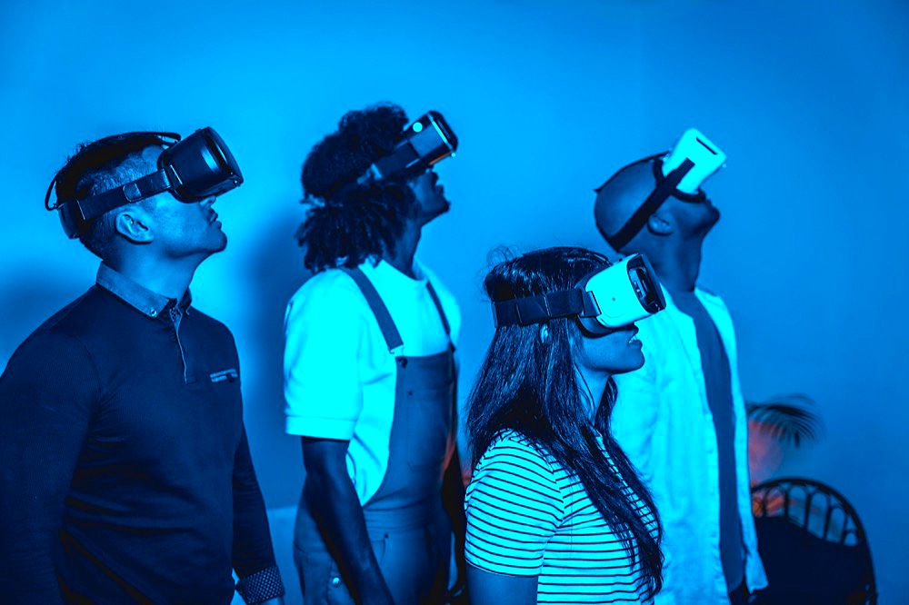 Group of young people with vr glasses in a virtual reality game in a blue light, futuristic or science, technology concept, looking to the right