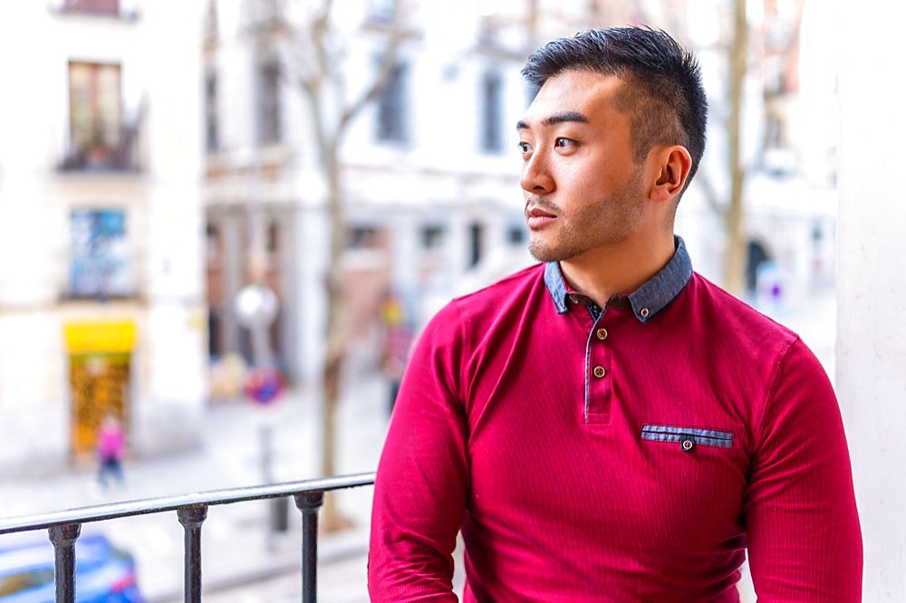 Portrait of a Chinese young man on a balcony at home, everyday situation, apartment