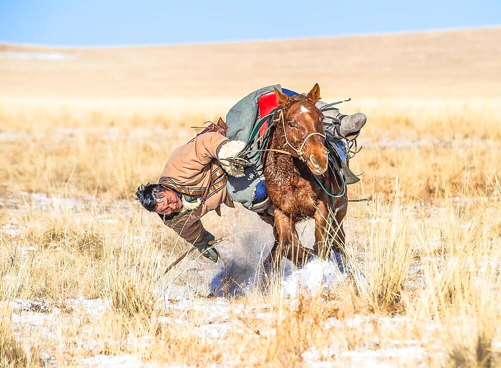 A rider picking up his pole from the ground. Dornod Province, Mongolia, Asia