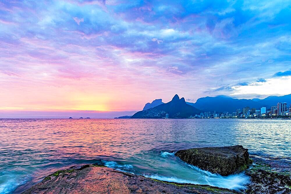 Dusk during the summer on Ipanema beach, Rio de Janeiro with the mountains and city lights in the background, Brasil