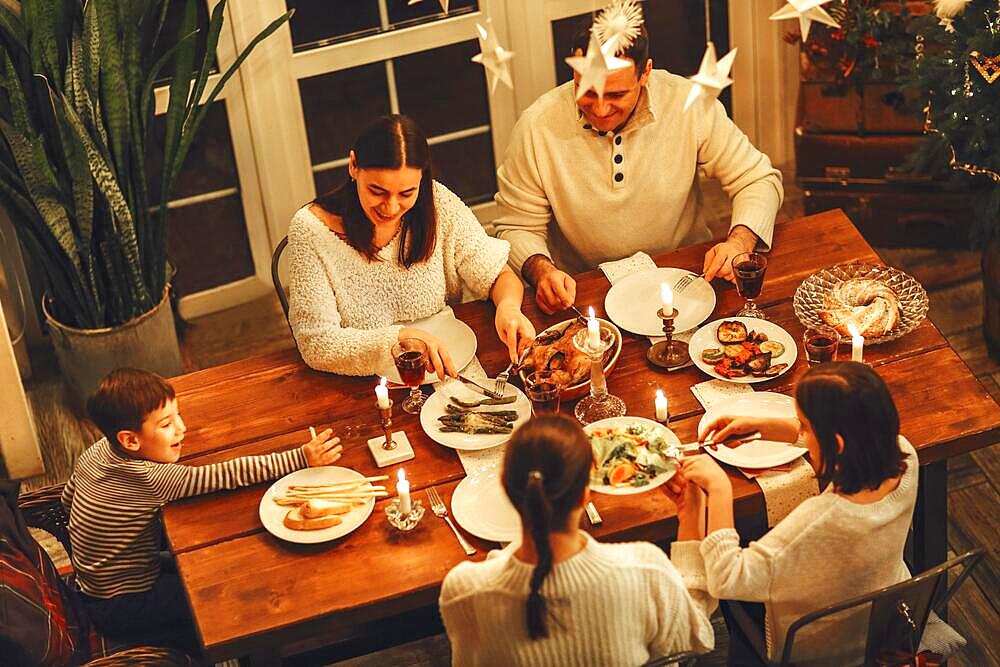 View from above of happy large family with many children celebrating Christmas or New Year eve together at cozy warm home, gathering around festive holiday table with delicious traditional xmas food