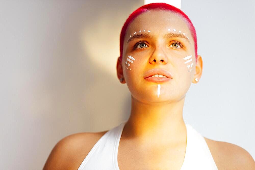 Beautiful relaxed woman with unusual make up and red shot hair while resting on sunny weekend day at home. Body positive concept